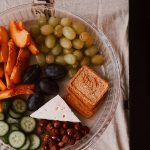 A delightful snack plate with fruits, cheese, and a laptop for a healthy lifestyle.